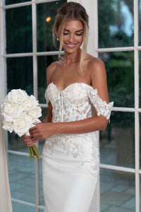 Ivory White Off The Shoulder Wedding Gown with Semi Sheer Corset Style Bodice, Sweetheart Off Shoulder Neckline, Lace Appliques, Fit and Flare Silhouette and Moderate Train