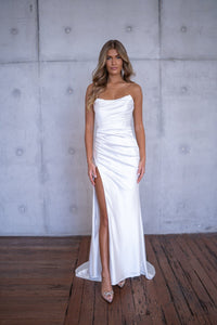 White bustier strapless fitted stretch satin wedding gown with draped pleats and high side slit