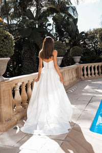 Lace up back design of white strapless ballgown wedding dress with a Basque waist, draped neckline and leg slit