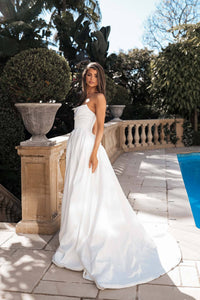 Side shot of white strapless ballgown wedding dress with a Basque waist, draped neckline, leg slit and sweep train