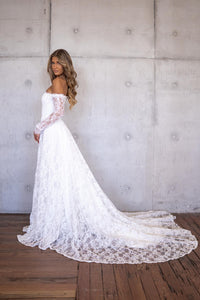 Side Image of Ivory White Off The Shoulder Long Sleeve Lace Wedding Gown featuring Sweetheart Neckline with Lace Trimming Detail, Sheer Long Sleeves, Corset Bodice, Basque Waistline, Full A-line Skirt and Long Train.