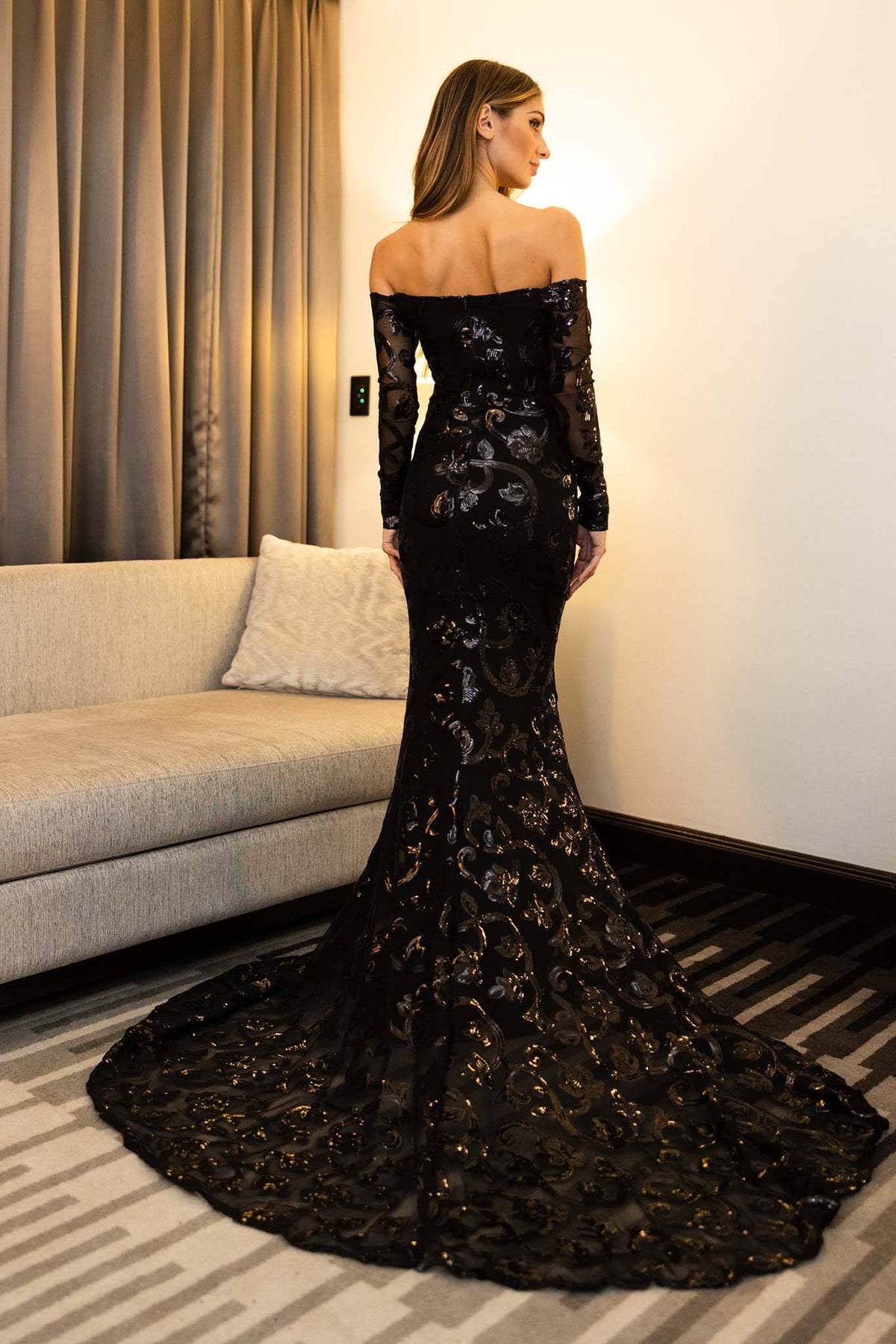 Sweep train and open shoulder design of Black sequin full length evening gown featuring vine pattern embroidered sequins, off-the-shoulder neckline, fit & flare mermaid silhouette 