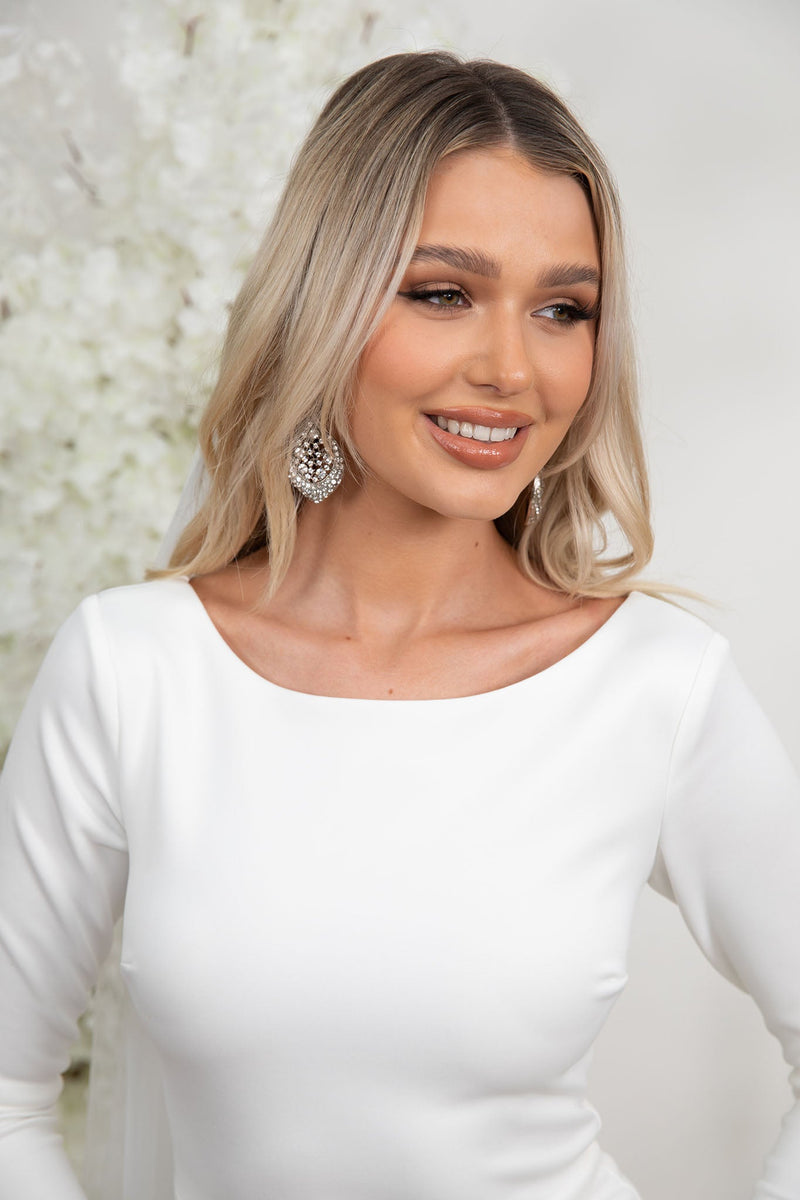 Close Up of Boat Neckline of Ivory White Long Sleeve Fitted Wedding Gown with Closed Back and Long Train worn with Extra Long Veil